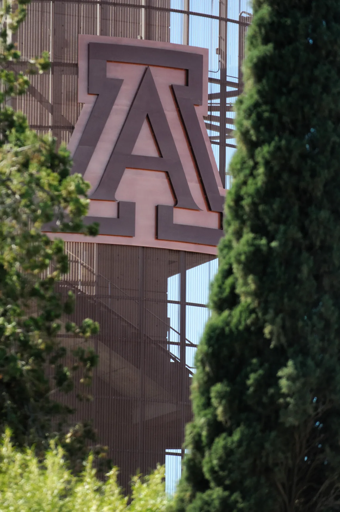 University A block logo in a metal frame with greenery around it. 